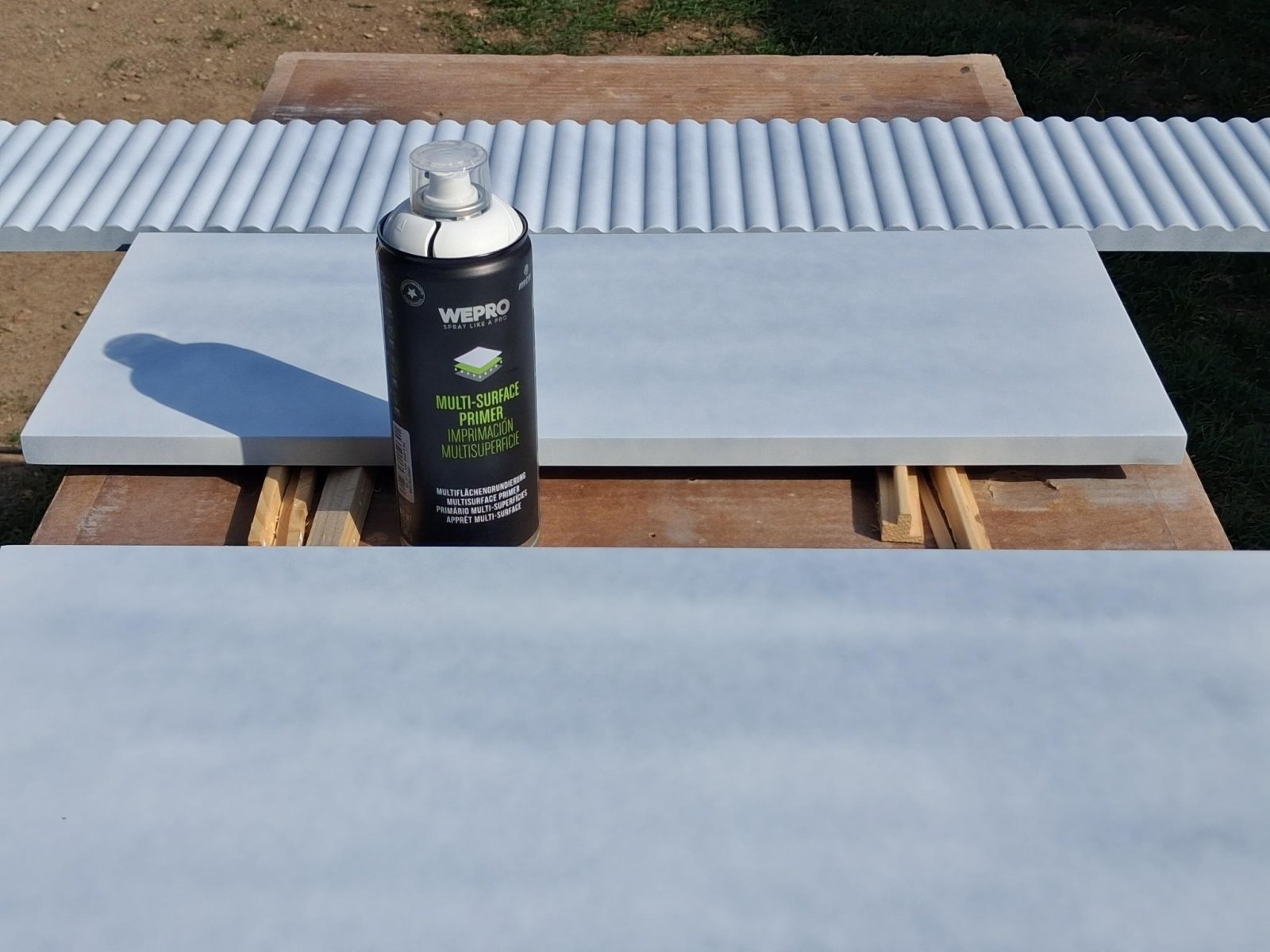 Világos alapozóval lefújt asztalelemek és a WEPRO Multi-Surface Primer flakonja